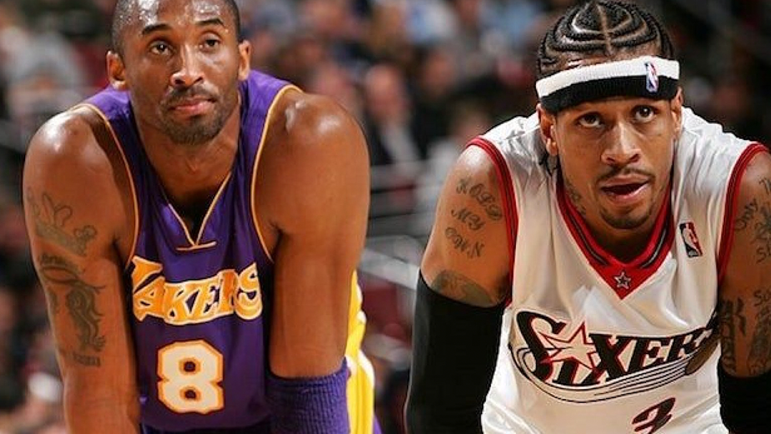 Two male basketball players Kobe Bryant and Allen Iverson in sports uniforms actively engaged in a game, showcasing athletic movement on an outdoor court.